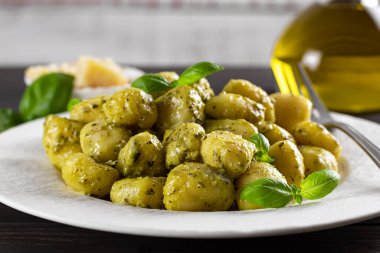 Pesto soslu sıcak kremalı patates gnocchi, taze fesleğen ve parmesan peyniri. Yüzeyin derinliği.