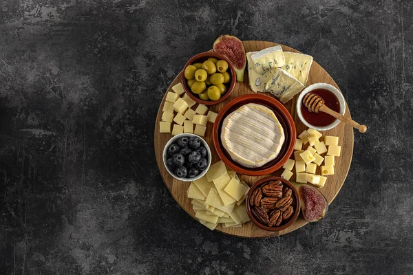 Vista superior de sabrosa tabla de quesos con bayas, miel, frutos secos, aceitunas y variedades de queso — Foto de Stock