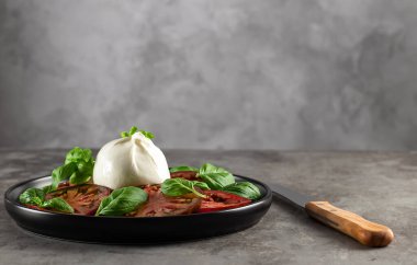 Bufalo burrata peyniri taze domates ve fesleğen yapraklarıyla servis edilir.. 