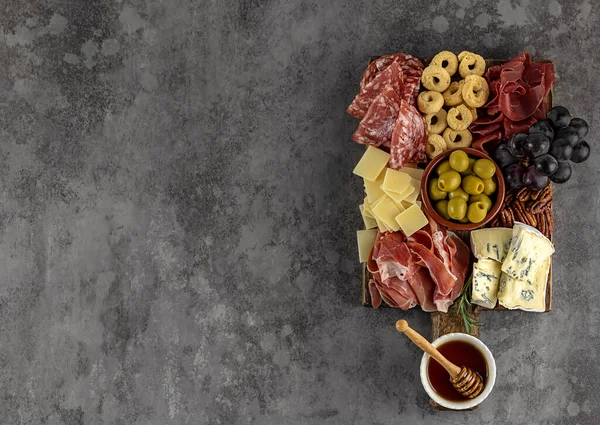 Bovenaanzicht van smakelijke charcuterie board met kaas, druiven, noten, olijven, en ham op een cirkel keukenbord — Stockfoto