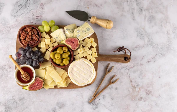 Sabrosa tabla de quesos con bayas, miel, frutos secos, aceitunas y variedades de queso — Foto de Stock