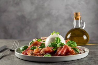 Lezzetli İtalyan aperatifleri. Taze domates, prosciutto ve fesleğen yapraklarıyla servis edilen bufalo burrata peyniri. Boşluğu kopyala.