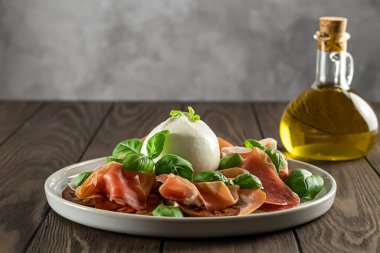 Lezzetli İtalyan aperatifleri. Taze domates, prosciutto ve fesleğen yapraklarıyla servis edilen bufalo burrata peyniri. Boşluğu kopyala.