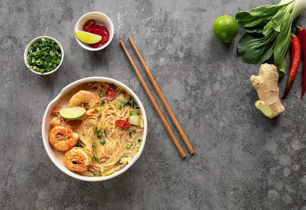 Laksa karides kasesi. Cam erişte tabağı, üst manzara, kopyalama alanı. Karidesli Asya yemeği, bok choy, limon, zencefil ve kırmızı biber. Latksa 'nın birçok çeşidi baharatlı hindistan cevizi çorbasıyla hazırlanır..