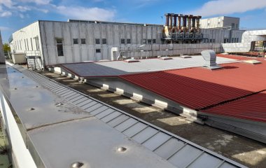 Bükülmüş metal levha içindeki eski bir sanayi binasının çatısı.