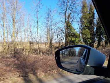 Arabanın dikiz aynası. Kışın kırsalda araba sürüyor.