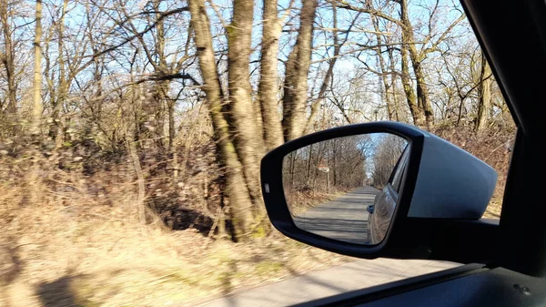 Rear view mirror of the car - driving in the countryside in winter
