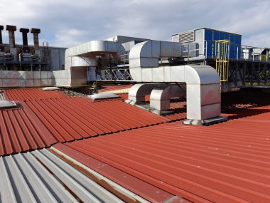 Bükülmüş metal levha içindeki endüstriyel bir binanın eski çatısındaki teknik sistem.