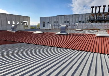 Bükülmüş metal levha içindeki endüstriyel bir binanın eski çatısındaki teknik sistem.