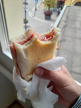 Atıştırmalık bir adamın elinde jambonlu sandviç.