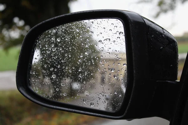 Rear view mirror of the car - driving in the countryside on an autumn day
