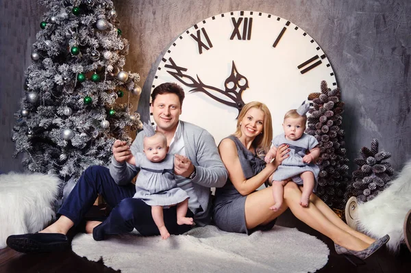 Mutlu, büyük bir aile ve evin içinde ikiz çocukları var. Büyük bir saatin arka planında..