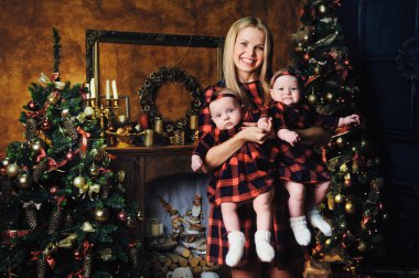 Mutlu bir anne ve ikiz çocukları Noel ağacının arka planında, evin içinde..