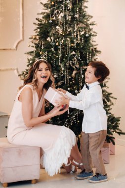 Anne oğluna Noel ağacının yanında bir Noel hediyesi veriyor. Mutlu bir aile..