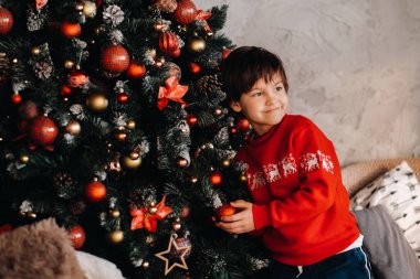 Evdeki Noel ağacında duran gülümseyen bir çocuğun portresi..