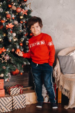 Evdeki Noel ağacında duran gülümseyen bir çocuğun portresi..