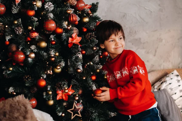 Evdeki Noel ağacında duran gülümseyen bir çocuğun portresi..