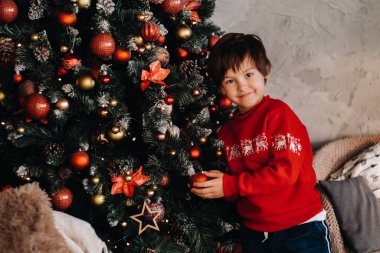 Evdeki Noel ağacında duran gülümseyen bir çocuğun portresi..