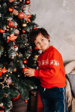 Evdeki Noel ağacında duran gülümseyen bir çocuğun portresi..