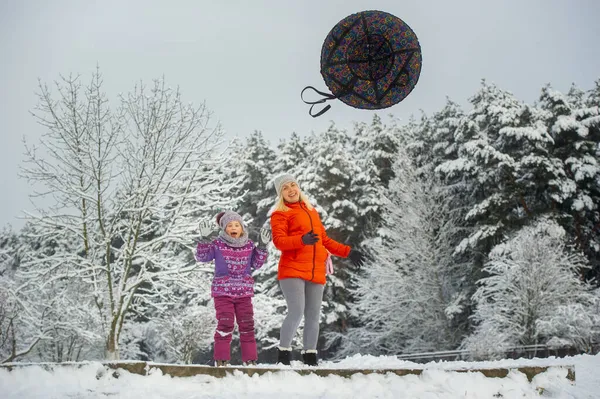 Famille mère et fille en hiver avec un cercle gonflable marcher à travers la forêt enneigée — Photo
