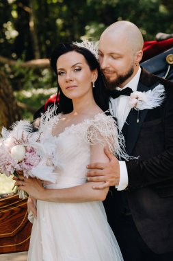 Gelin ve damadın bir çifti arabanın yanında dikiliyorlar..