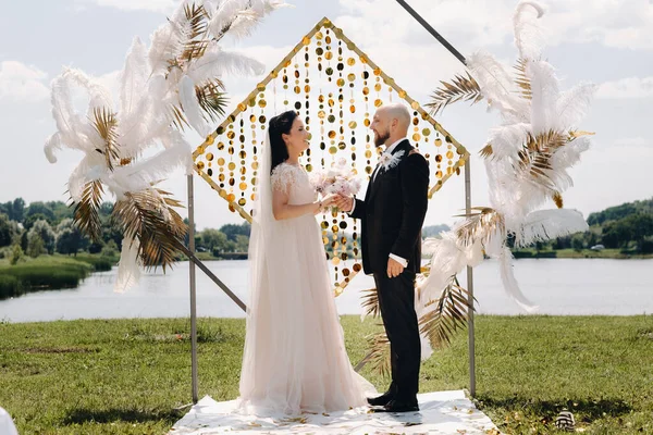 Düğün sırasında düğün kemerinin yanında mutlu bir çift..