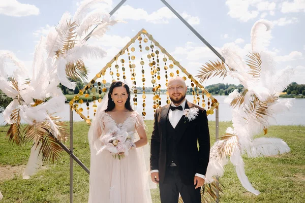 Düğün töreninde kemerin yanında mutlu bir çift var..