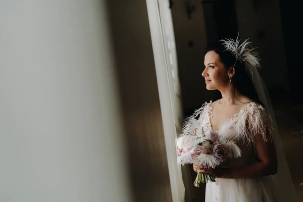 Невеста Свадебном Платье Букетом Стоит Старого Окна Смотрит — стоковое фото