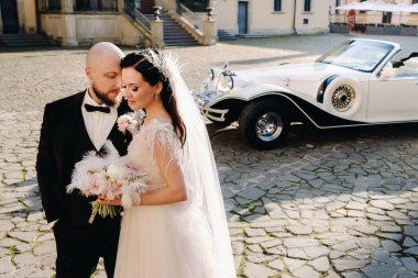 Şatonun avlusunda, eski bir arabanın yanında zarif bir çift..