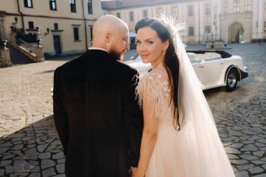 Şatonun avlusunda, eski bir arabanın yanında zarif bir çift..