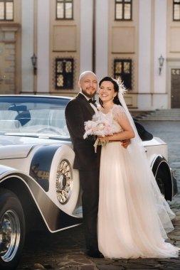 Şatonun avlusunda, eski bir arabanın yanında zarif bir çift..