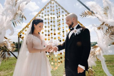 Düğün töreninde kemerin yanında yüzük takan mutlu bir çift..