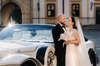 Şatonun avlusunda, eski bir arabanın yanında zarif bir çift..