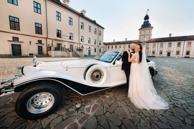 Şatonun avlusunda, eski bir arabanın yanında zarif bir çift..