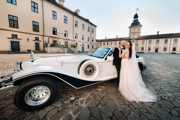 Şatonun avlusunda, eski bir arabanın yanında zarif bir çift..