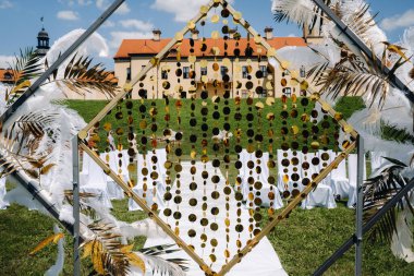 Eski bir şatonun arka planında süslü bir düğün kemeri. Eski tarz tüylerle süslenmiş bir düğün seremonisi..