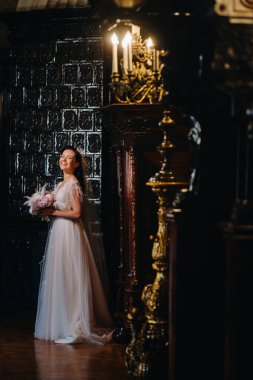 Gelinlik giymiş gelin ve elinde buket kalenin eski iç kısmında duruyor..