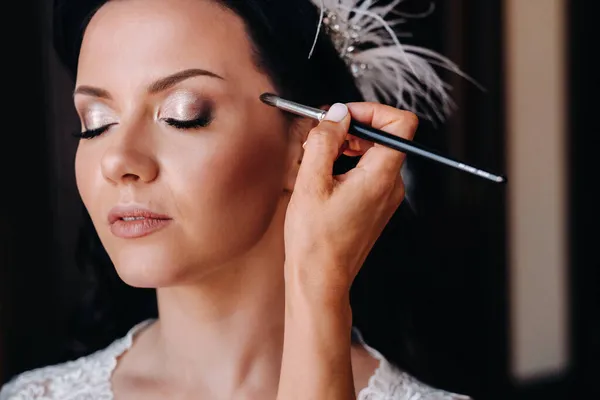 The makeup artist does the bride\'s makeup.Morning of the bride.