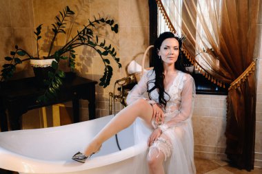 Gelin, şeffaf bir elbise ve iç çamaşırı giymiş ve klasik bir küvette oturuyor. Gelinin sabahı.