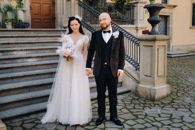 Gelin ve damat Nesvizh Kalesi 'nin merdivenlerinden çıkıyorlar. Düğün çifti sarayın merdivenlerinden iniyor..