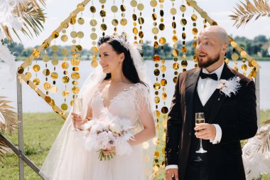 Düğün sırasında düğün kemerinin yanında mutlu bir çift..