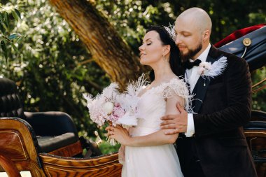 Gelin ve damadın bir çifti arabanın yanında dikiliyorlar..