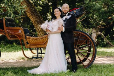 Gelin ve damadın bir çifti arabanın yanında dikiliyorlar..