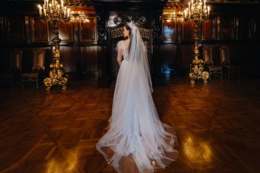 Gelinlik giymiş bir gelin, arkası dönük olarak kalenin içinde durur..