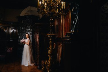 Gelinlik giymiş gelin ve elinde buket kalenin eski iç kısmında duruyor..