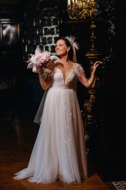 Gelinlik giymiş gelin ve elinde buket kalenin eski iç kısmında duruyor..