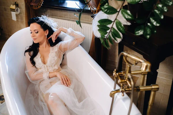 Gelin, şeffaf bir elbise ve iç çamaşırı giymiş, eski bir banyoda yatıyor. Gelinin sabahı.