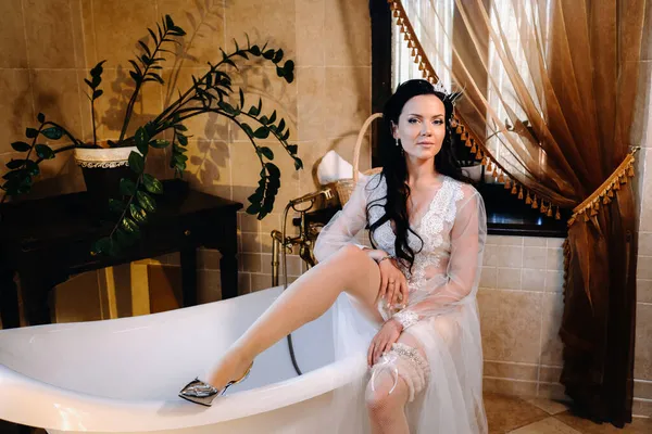 Gelin, şeffaf bir elbise ve iç çamaşırı giymiş ve klasik bir küvette oturuyor. Gelinin sabahı.