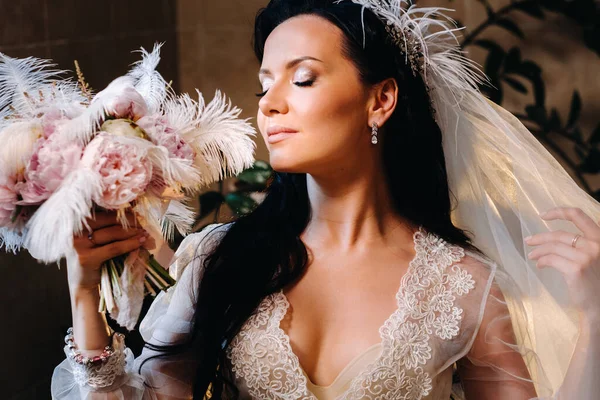 Gelin, şeffaf bir elbise ve iç çamaşırı içinde, elinde bir tüyle eski bir banyonun yanında oturuyor, gelinin sabahında..