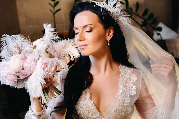 Gelin, şeffaf bir elbise ve iç çamaşırı içinde, elinde bir tüyle eski bir banyonun yanında oturuyor, gelinin sabahında..